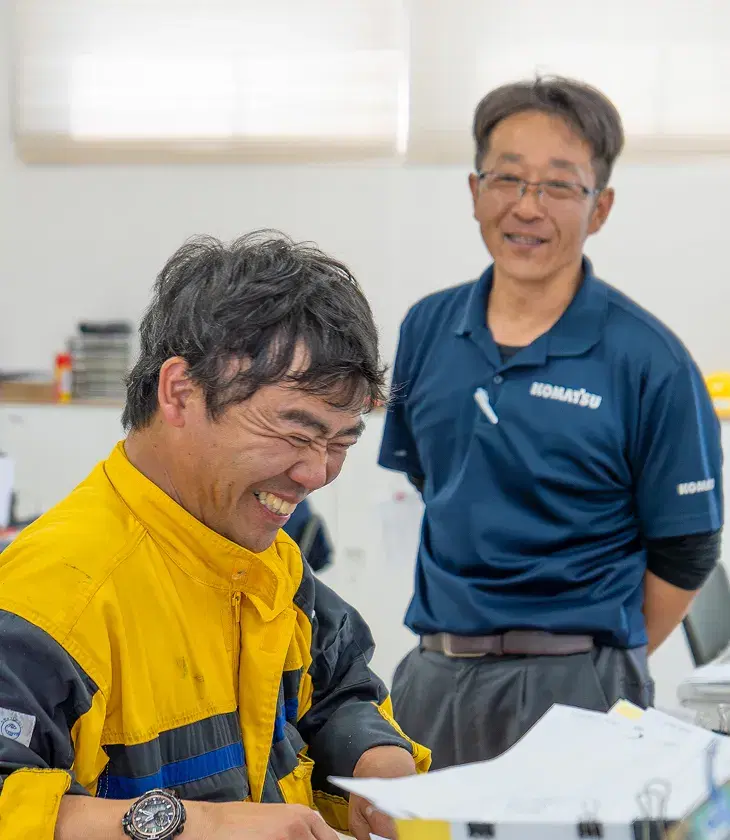 笑顔で話す作業服姿の社員