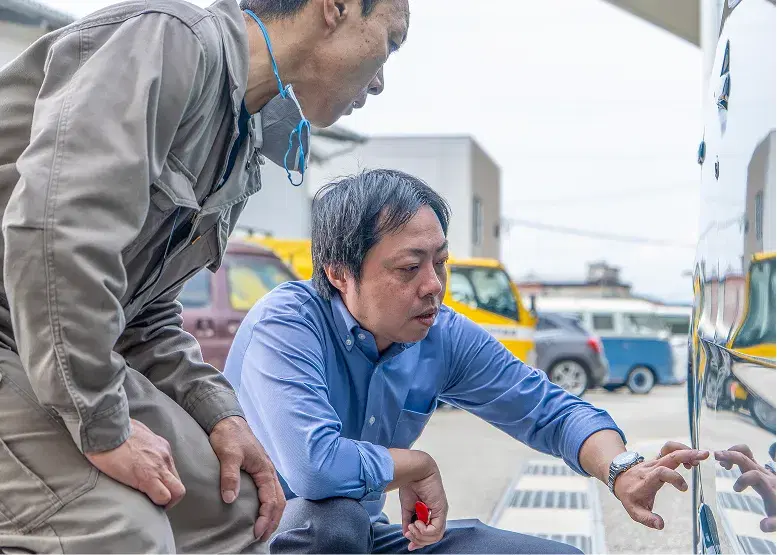 屋外で車両の整備に取り組むスタッフ