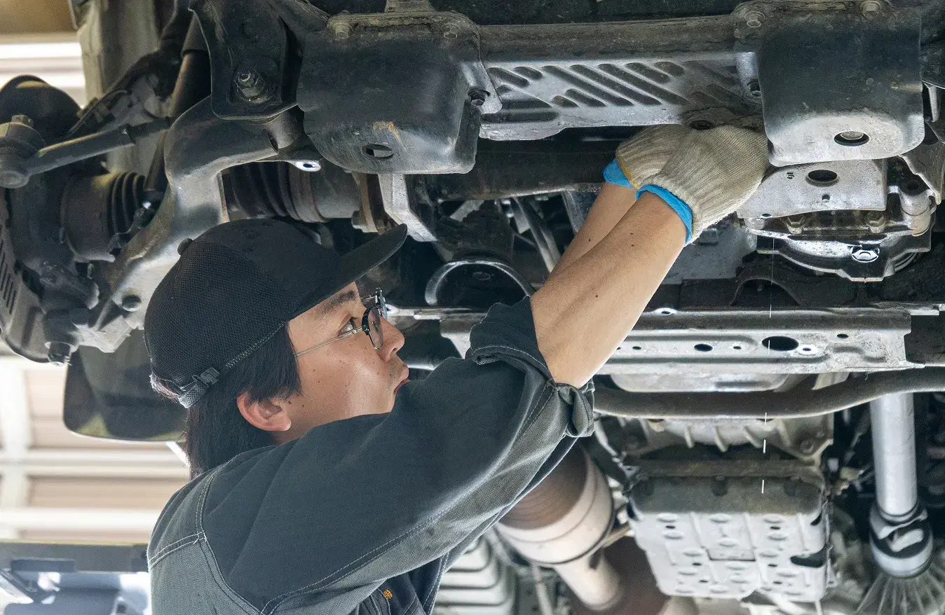 車体の下から足回りを点検する整備士